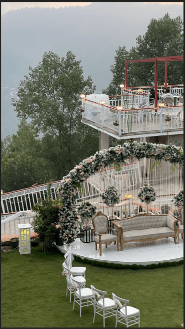 White guest chairs on the lawn facing the floral nikah stage